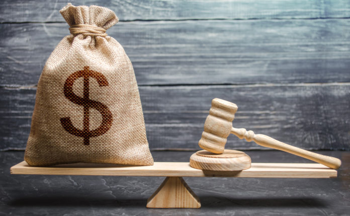 Bag of money with a dollar sign and a judge's hammer on the scales. Concept lobbying for the adoption of a law or a norms, corruption. Payment of fines and penalties. award of compensation for damage